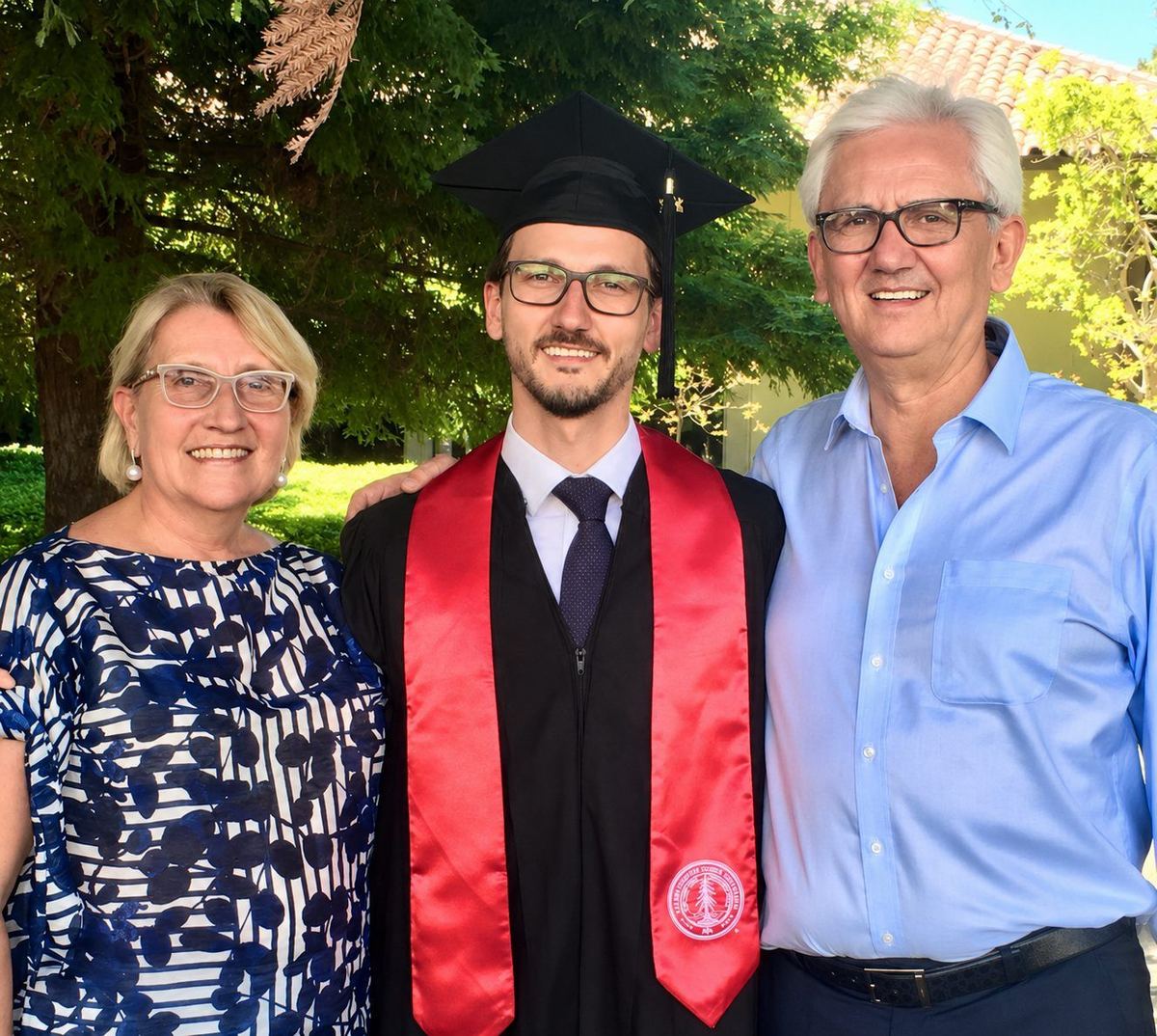 Roberto in graduation cap and gown with his parents